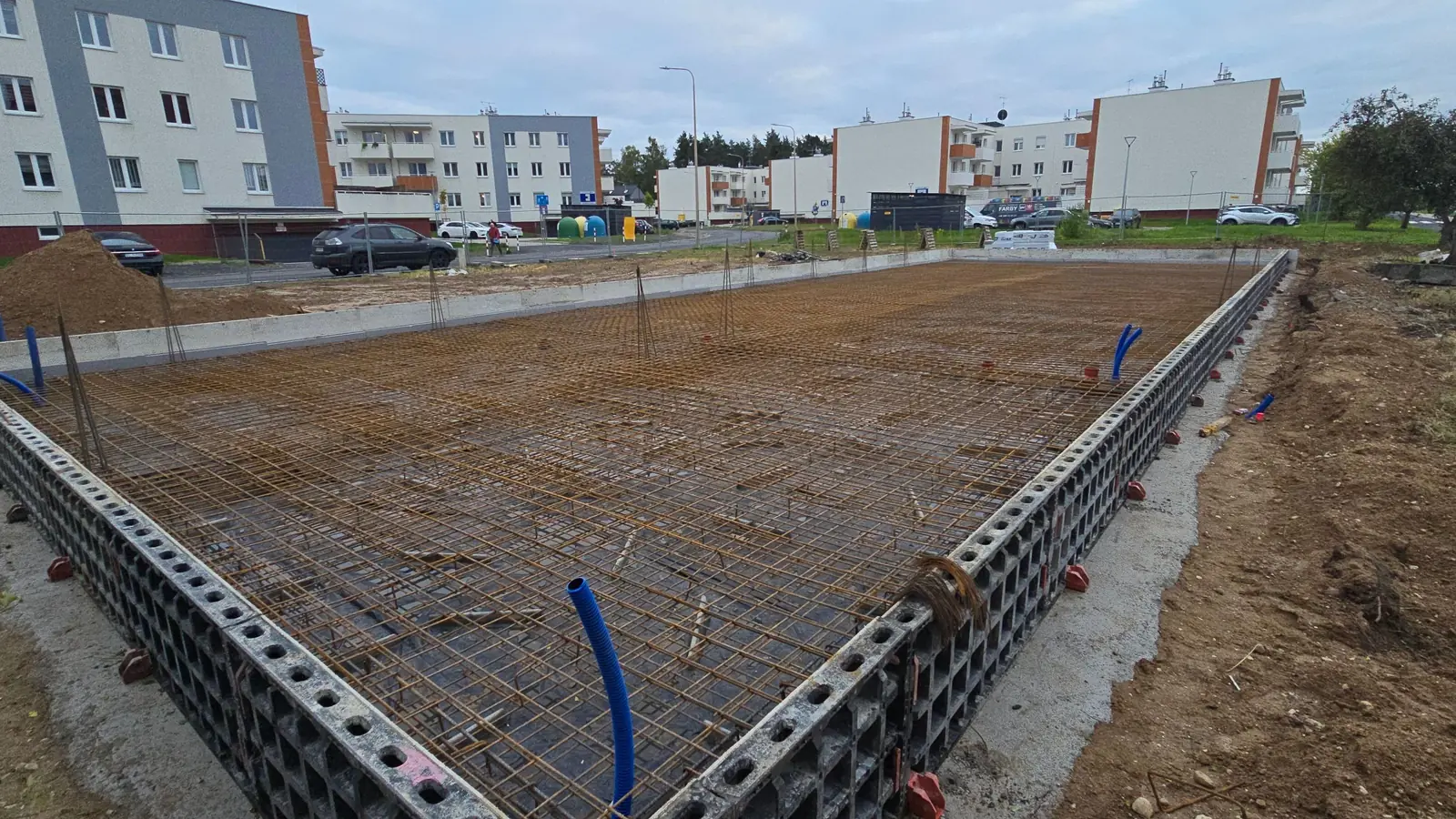 Siatki zbrojenia płyty fundamentowej w szalunku systemowym, z niebieskim przepustem instalacyjnym